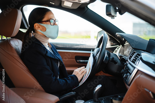 Business woman sitting in a car in face mask © Drobot Dean