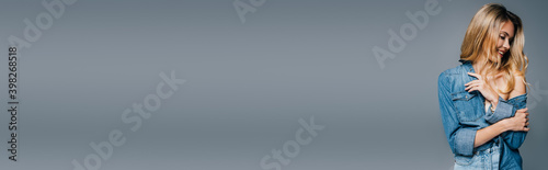 smiling, charming woman in denim shirt posing with naked shoulder isolated on grey, banner © LIGHTFIELD STUDIOS