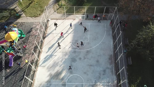 aerial view of street basketball court and children playground. kids are playing football at the sunset.