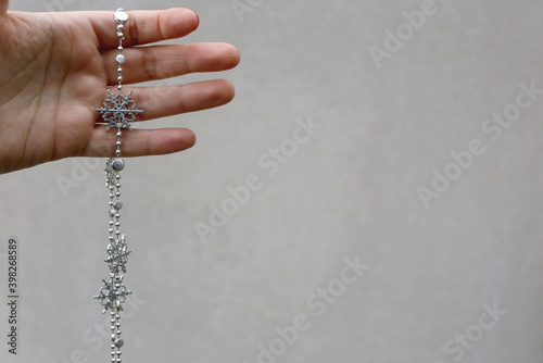 Hand holding snowflake garland. Selective focus, plain background.