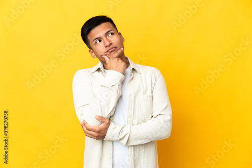Young Ecuadorian man isolated on yellow background thinking an idea while looking up © luismolinero
