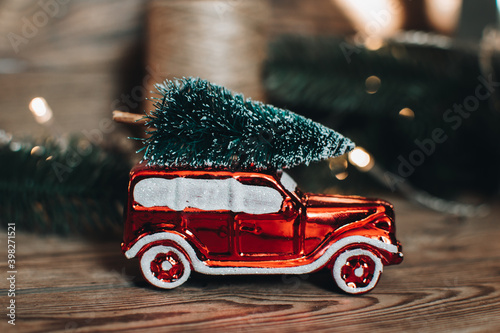 Vintage retro car with christmas tree on the roof. Scandinavian hygge styled Christmas composition. Fir tree, vintage Christmas tree toys. Winter cozy vintage flat lay. New Year holidays. 