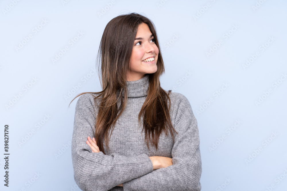 Teenager Brazilian girl over isolated blue background looking up while smiling Teenager Brazilian girl over isolated blue background looking up while smiling