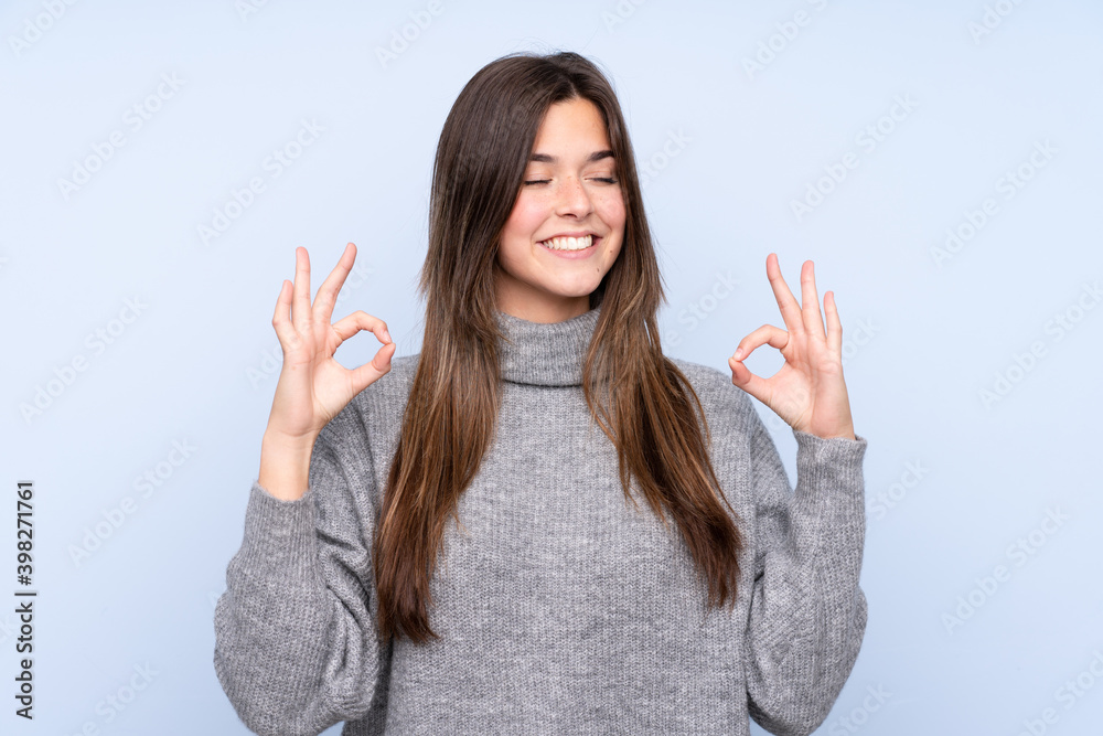 Teenager Brazilian girl over isolated blue background in zen pose Teenager Brazilian girl over isolated blue background in zen pose