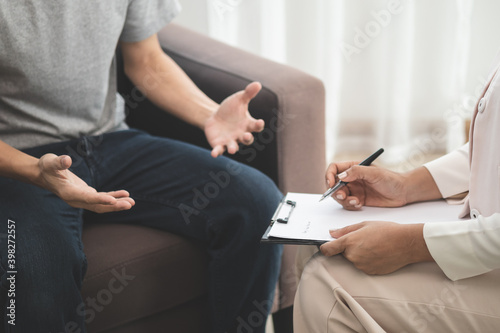Psychiatrist taking notes to find out how to treat the therapist.Young man has mental symptoms which must have been therapy, sitting on couch to consult to psychologist during the session.