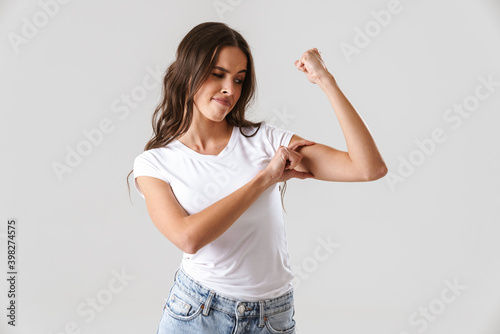 Photo Pleased beautiful girl showing her bicep at camera