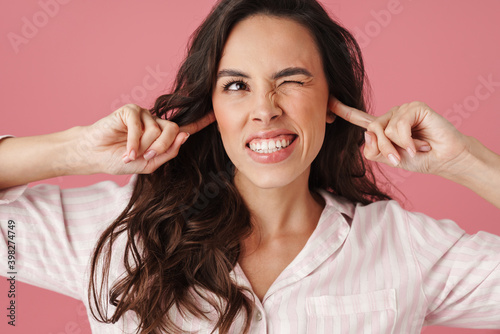 Fototapeta Naklejka Na Ścianę i Meble -  Displeased beautiful woman winking while plugging her ears