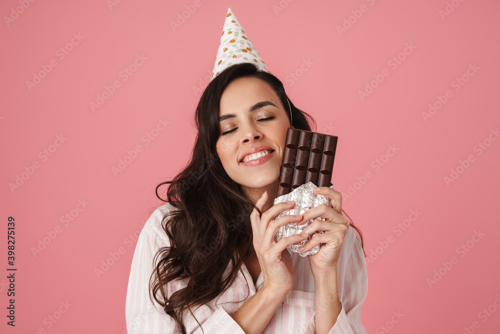 Joyful woman in party cone smiling while posing with chocolate Joyful woman in party cone smiling while posing with chocolate