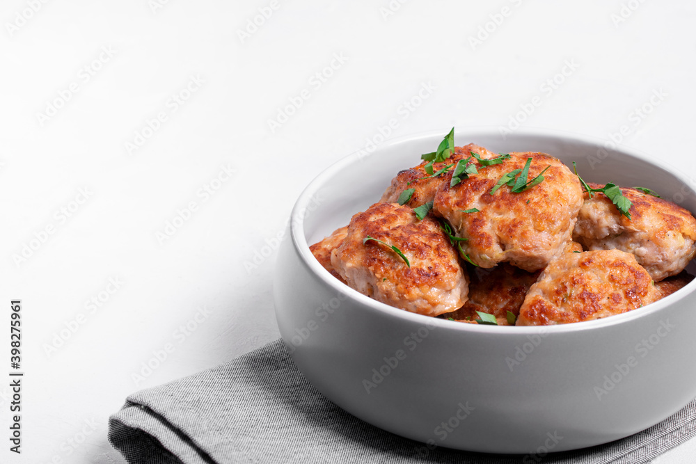 Meat cutlets with mixed mince in the ceramic bowl on the white table. Hot homemade meal. Copy space Meat cutlets with mixed mince in the ceramic bowl on the white table. Hot homemade meal. Copy space
