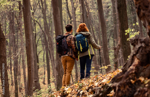 Rear view of two young hikers with backpack walking in forest.