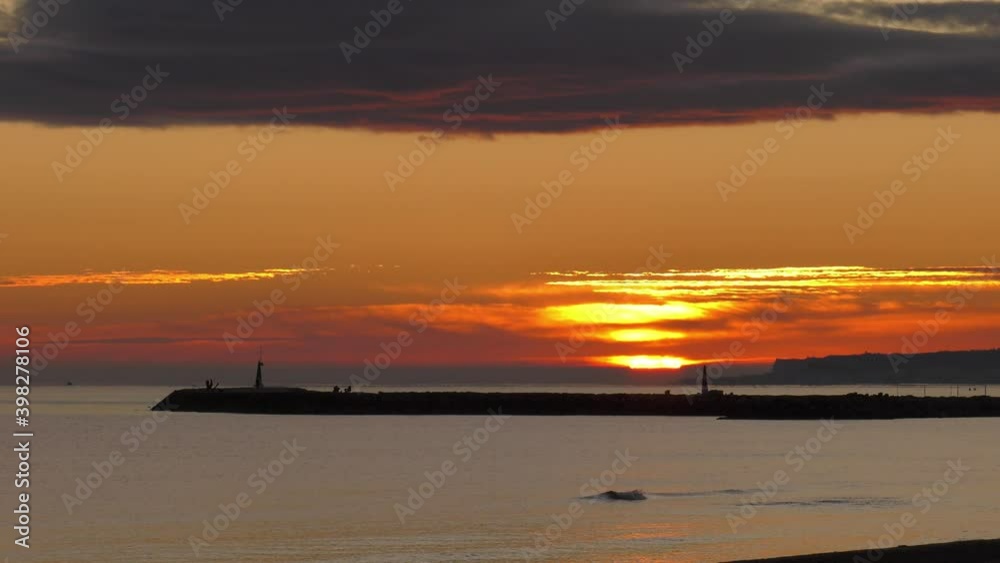 Peaceful sunrise over calm ocean and harbor sea wall Peaceful sunrise over calm ocean and harbor sea wall