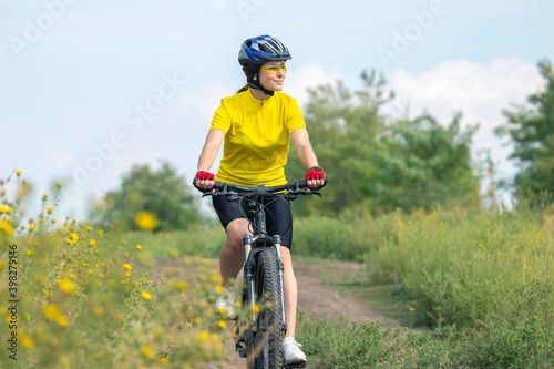beautiful and happy woman cyclist rides a bicycle on the road in nature. Healthy lifestyle and sports. Leisure and hobbies