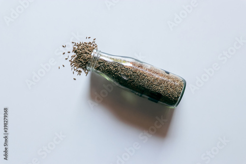 Dry cumin in glass bottle and heap of cumin isolated on white background. top view shot.