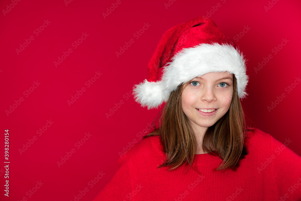 pretty young girl with Santa Claus cap and red pullover in front of red background pretty young girl with Santa Claus cap and red pullover in front of red background