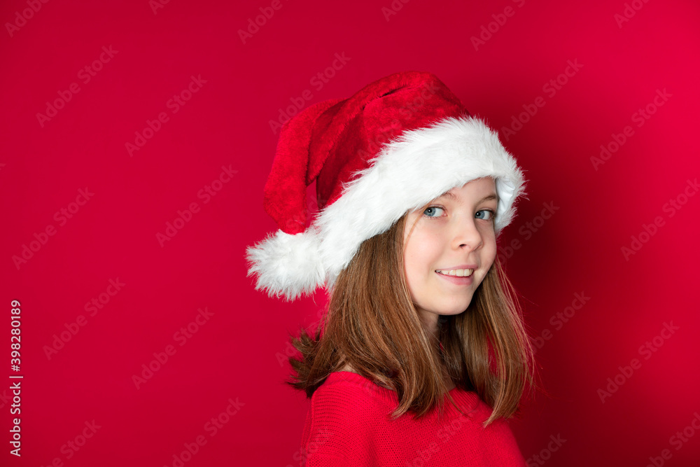 pretty young girl with Santa Claus cap and red pullover in front of red background pretty young girl with Santa Claus cap and red pullover in front of red background
