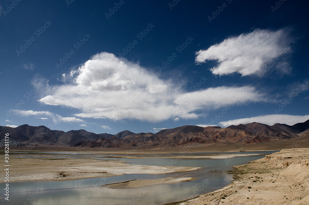 Scenic view of a river into a plateau under big white clouds