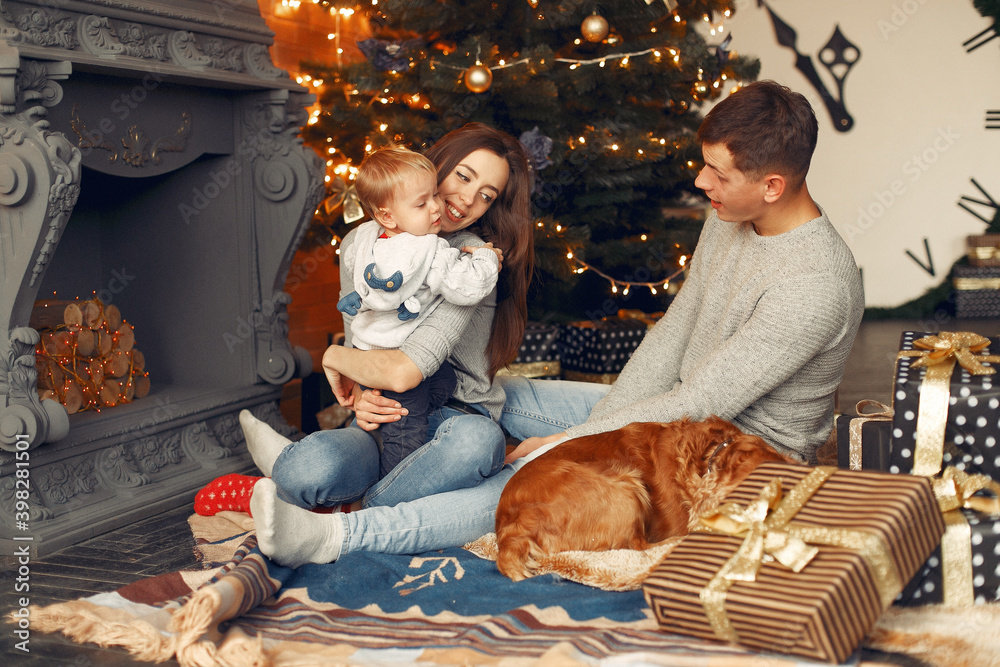 Mother in a gray sweater. Family with christmas gifts. People near fireplace. Family with dog.