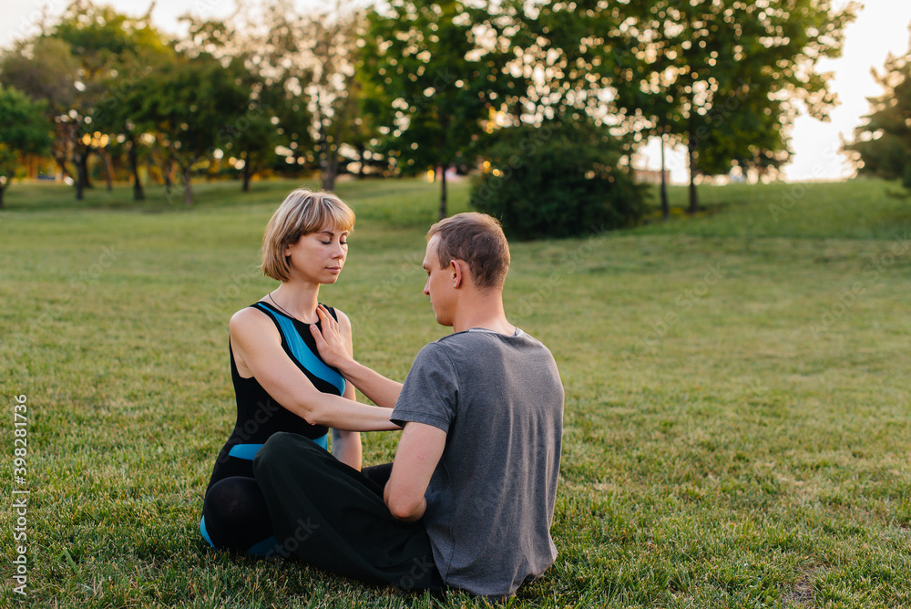 A group of people perform paired yoga exercises in a Park during sunset. Healthy lifestyle, meditation and Wellness A group of people perform paired yoga exercises in a Park during sunset. Healthy lifestyle, meditation and Wellness