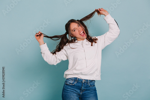 Funny laughting woman playing with her hair making faces and dancing over isolated background photo