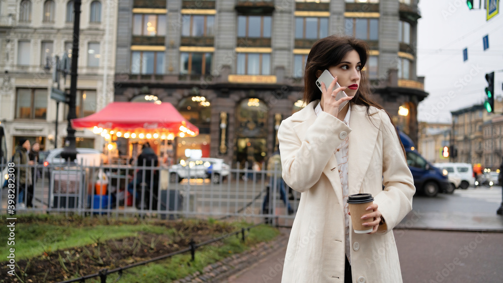 Fototapeta premium Business woman with coffee in hands speaks on the phone