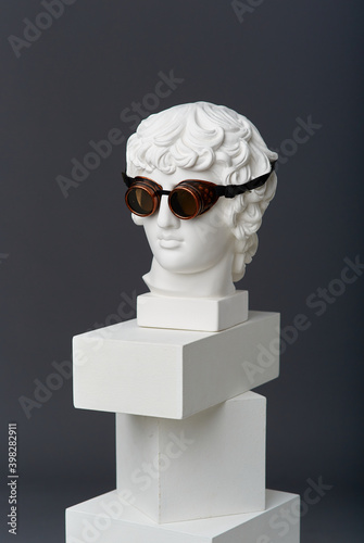 Plaster head of Antinous with round glasses. The concept of the absurd and the combination of the incongruous photo
