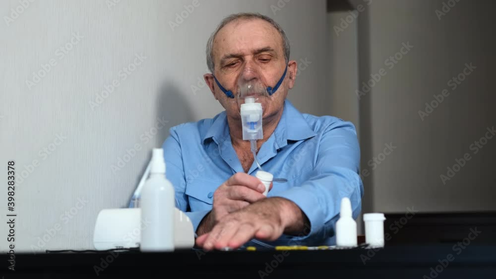 Senior Man Using Nebulizer for Inhalation and Looking at Prescription Pills Due to Coronavirus Pandemic. Slow Motion. Respiratory Problem, Allergy and Asthma Bronchitis Virus Healing Concept Senior Man Using Nebulizer for Inhalation and Looking at Prescription Pills Due to Coronavirus Pandemic. Slow Motion. Respiratory Problem, Allergy and Asthma Bronchitis Virus Healing Concept
