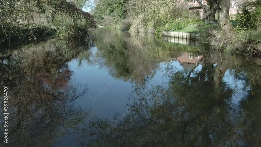 Aerial low along river with reflections of trees in still water Aerial low along river with reflections of trees in still water