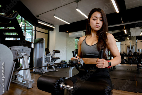 Young beautiful woman in sportswear working out with machine in gym