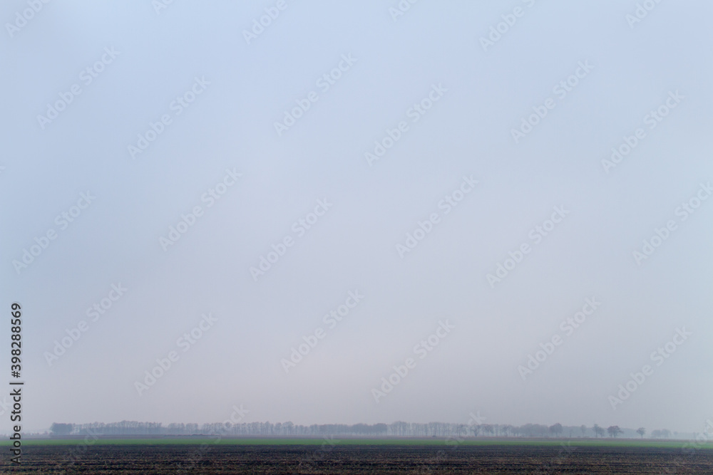 Landscape view with very low angle horizon on a cold and hazy day, lots of copy space in sky