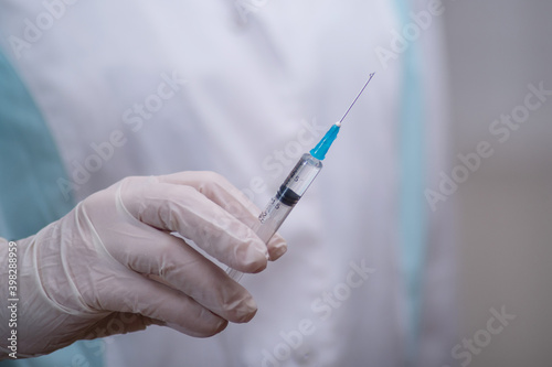 The concept of inoculation, vaccination or treatment of the disease. Close-up of the doctor's gloved hand holding a medical syringe
