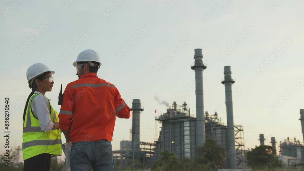 successful engineer teamwork concept caucasian male supervisor manager and asian female engineer working with safety helmet discussion consult with oil refinery industry plant background