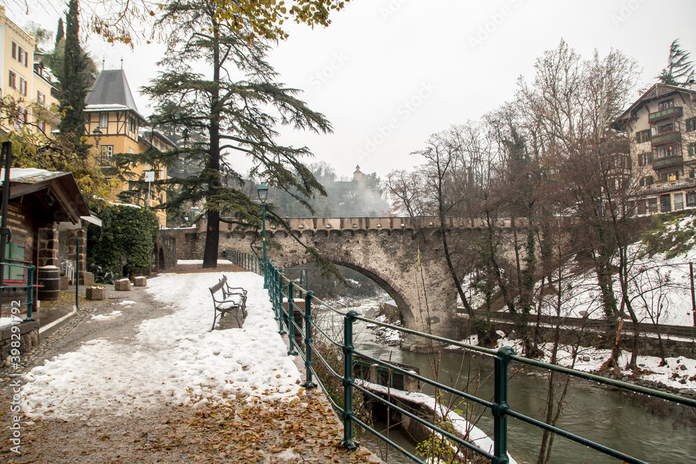Roman bridge (ponte romano - Römerbrücke) on the promenade with snow in winter in Merano South Tyrol Italy