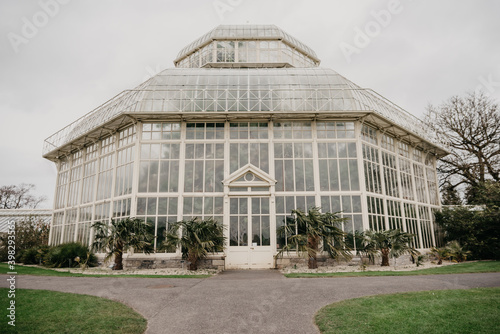 Front view of a greenhouse surrounded with two sidewalks, green grass and other plants in Dublin