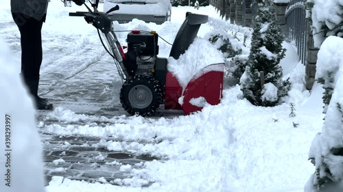 Man clearing the snow off the driveway with a snow blower
