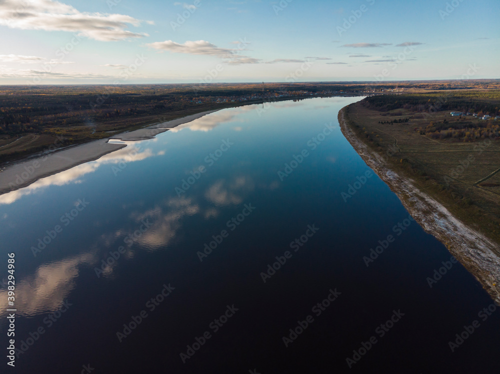 Two banks of a large river. Reflection of the sky in the water