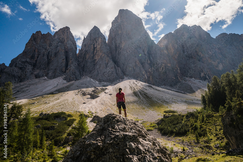 Young hiker with the back at the camera looking towards the cliffs in the Dolomites, Italy.