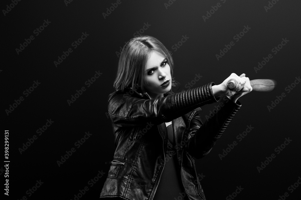 Obraz premium Monochrome studio portrait of young beautiful woman in a leather jacket, red underwear Looks into the camera and beats a wooden baseball bat