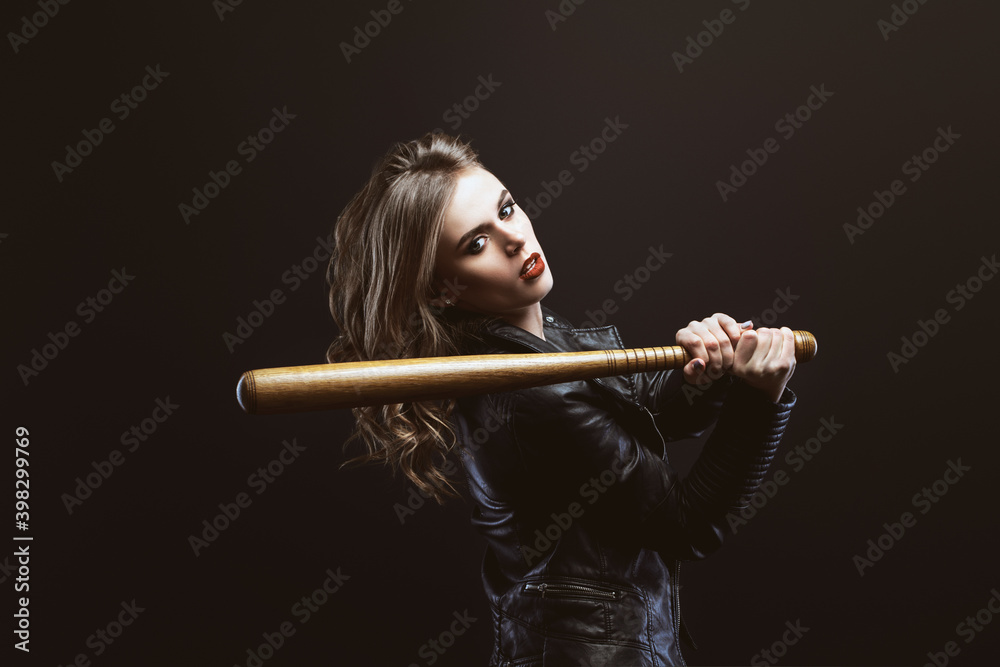 Portrait of young blonde beautiful woman in a leather jacket with wooden baseball bat Looks into the camera Portrait of young blonde beautiful woman in a leather jacket with wooden baseball bat Looks into the camera