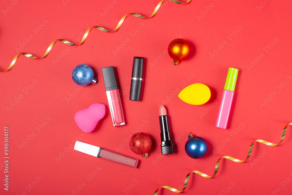 A set of cosmetics, lipstick and lip glosses, brush, mascara on a bright red background. The concept of buying cosmetics, online store, holiday