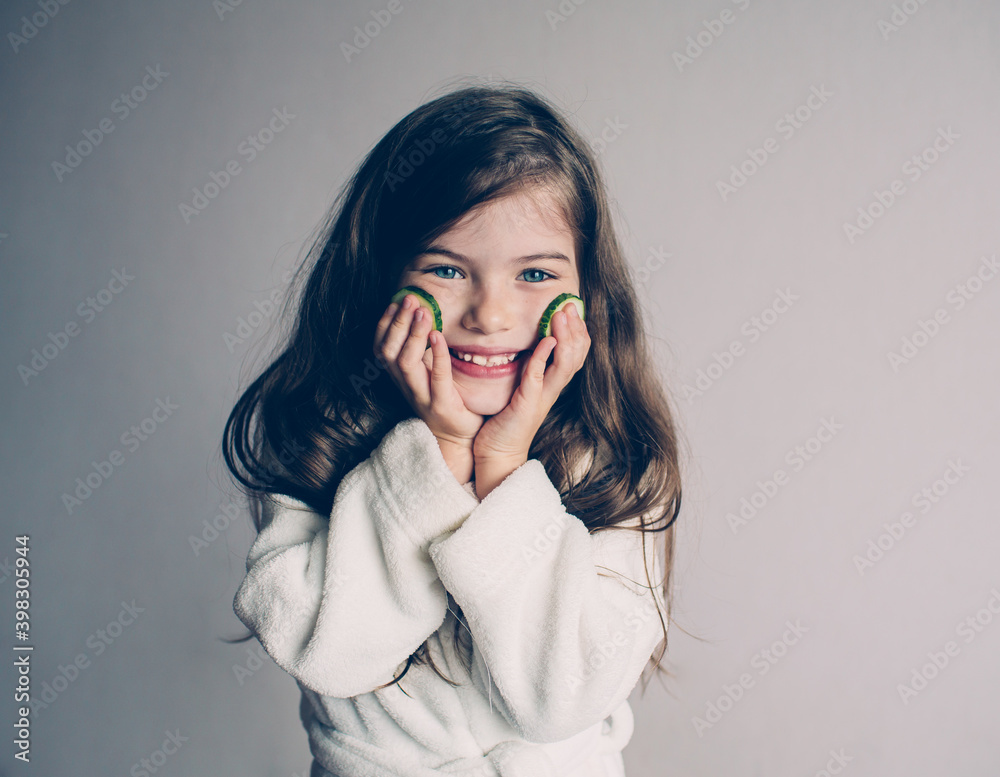 Funny little girl with cucumbers on her face ,beauty and health concept, closeup portrait.