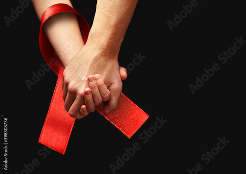 World AIDS Day. Holding hands with red ribbon. photo