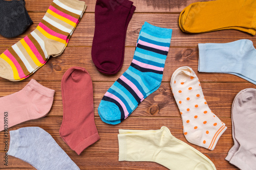 multicolored new socks in different sizes stacked on a wooden background. clothes for women