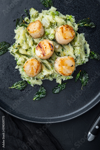 Seafood, scallops grilled with minty potatoes and peas, flat lay, on black textured background