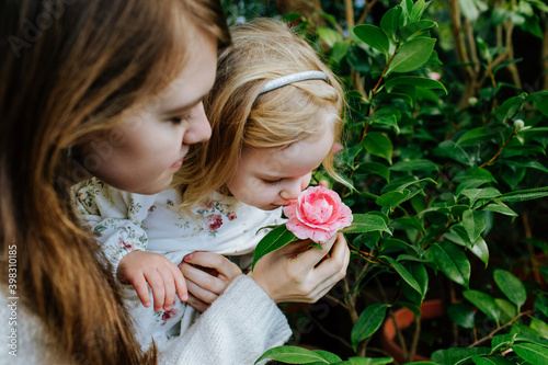 Mother and daughter smelling flower while walking in orangery photo