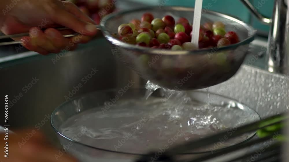 A woman washes berries in a colander. White and red currants. Fresh gooseberry close up view. A woman washes berries in a colander. White and red currants. Fresh gooseberry close up view.