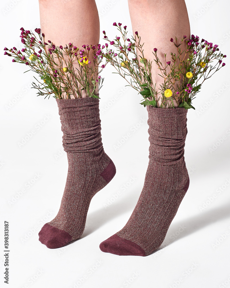 © Yaroslav Danylchenko/Stocksy - Woman wearing brown socks with wild flowers sticking out. © Yaroslav Danylchenko/Stocksy - Woman wearing brown socks with wild flowers sticking out.