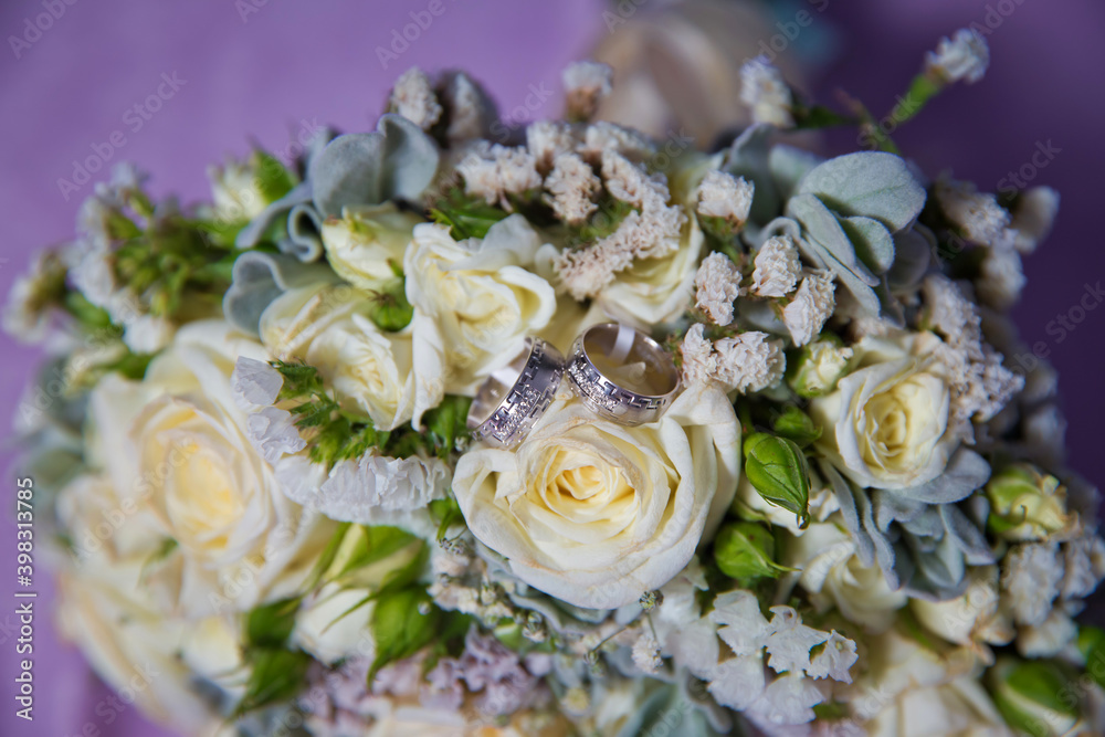 Gold rings for a wedding on a bouquet of flowers. White wedding rose bouquet . Bouquet of white roses. Gold rings for a wedding on a bouquet of flowers. White wedding rose bouquet . Bouquet of white roses.