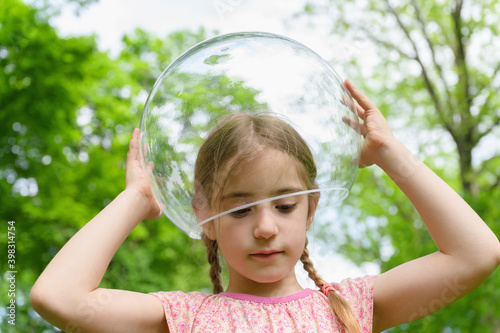 Little Girl Putting Bubble on her Head Outdoors photo