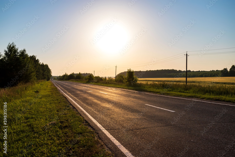 Asphalt road going through the countryside going into the distance. Summer travel concept.