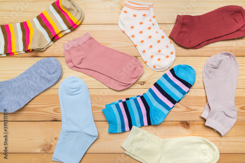 multicolored new socks in different sizes stacked on a wooden background. clothes for women